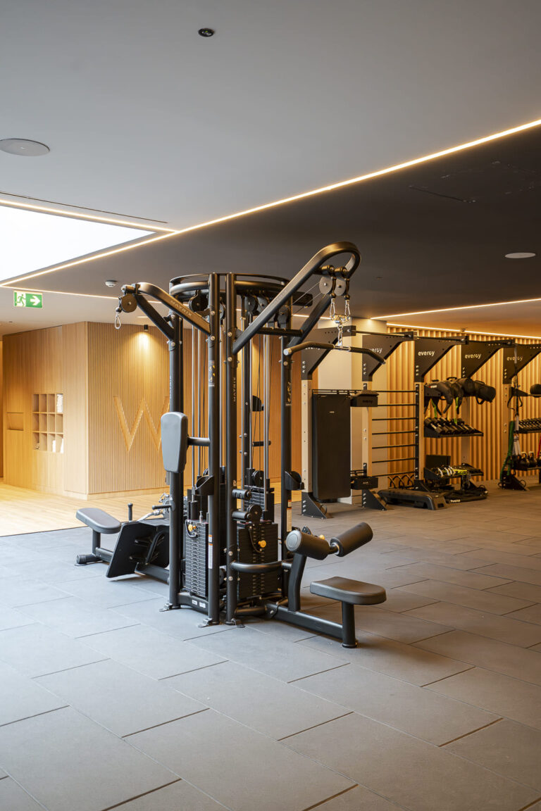 Máquina de entrenamiento en un gimnasio con paredes de madera y suelo de cerámica.