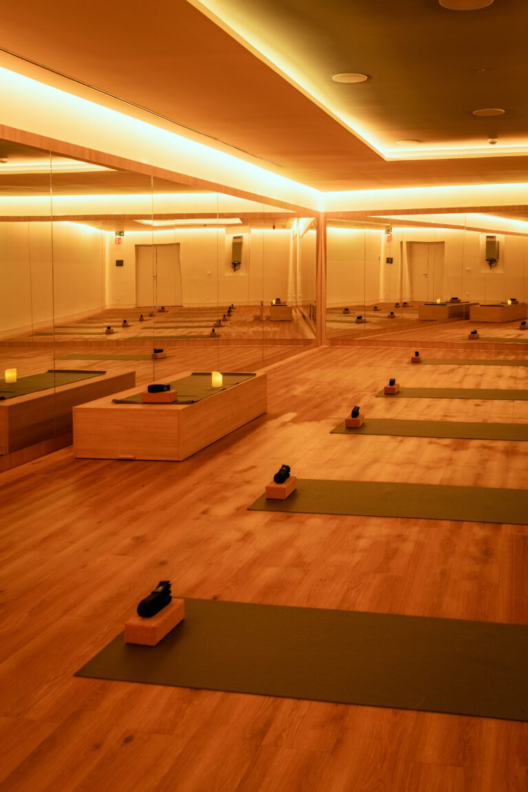 Sala de yoga con luz cálida, esterillas y espejos en las paredes