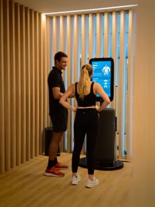 Entrenador y cliente observando una pantalla interactiva en un centro deportivo